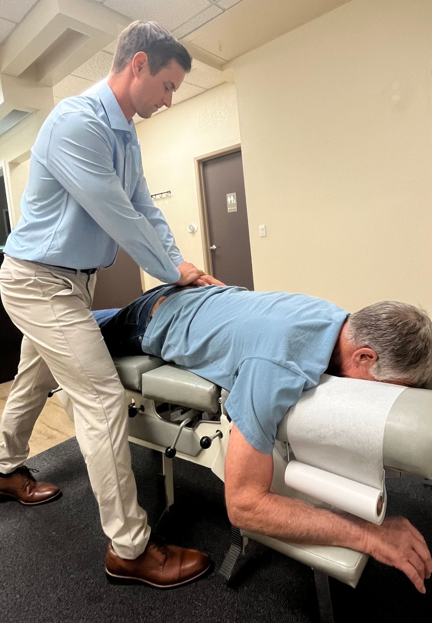 Dr. Hill adjusting the lower back of a patient lying face down on a chiropractic table